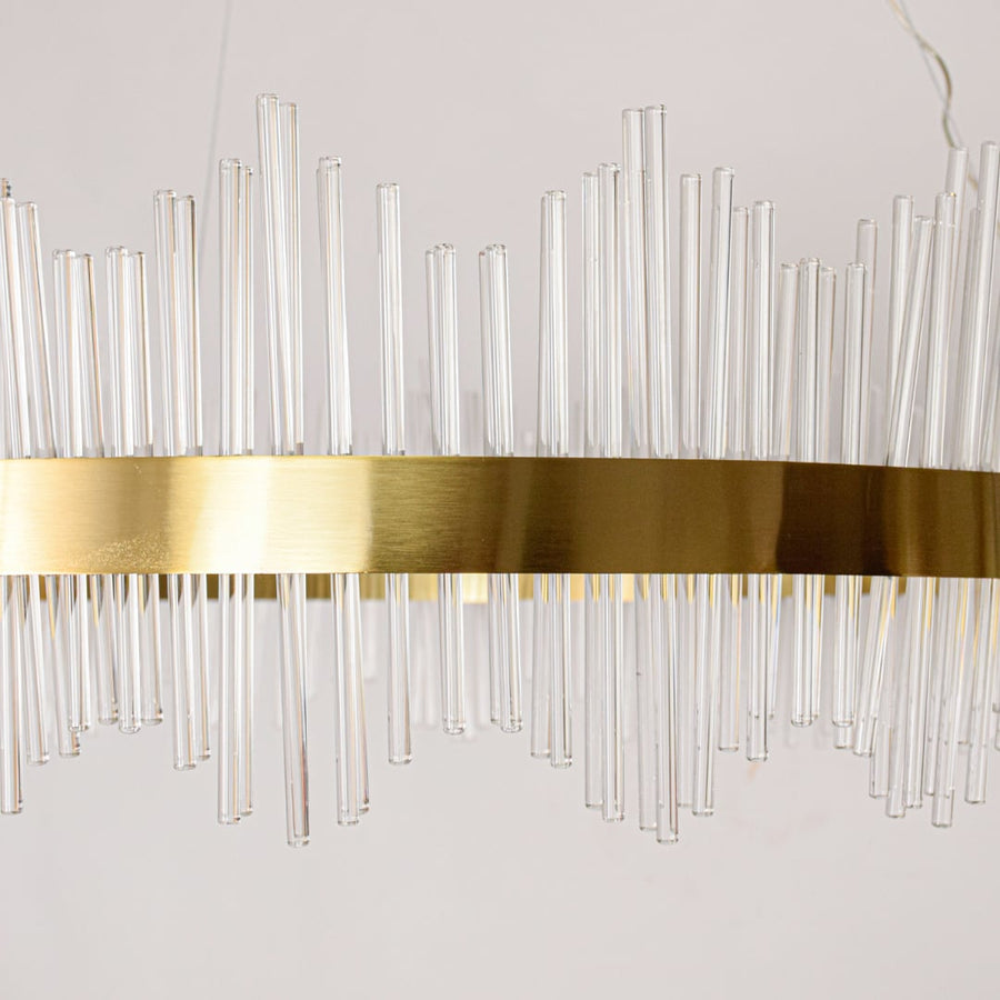 Closeup of gold metal chandelier band with clear glass rods showing refined craftsmanship and premium luxury lighting detail.