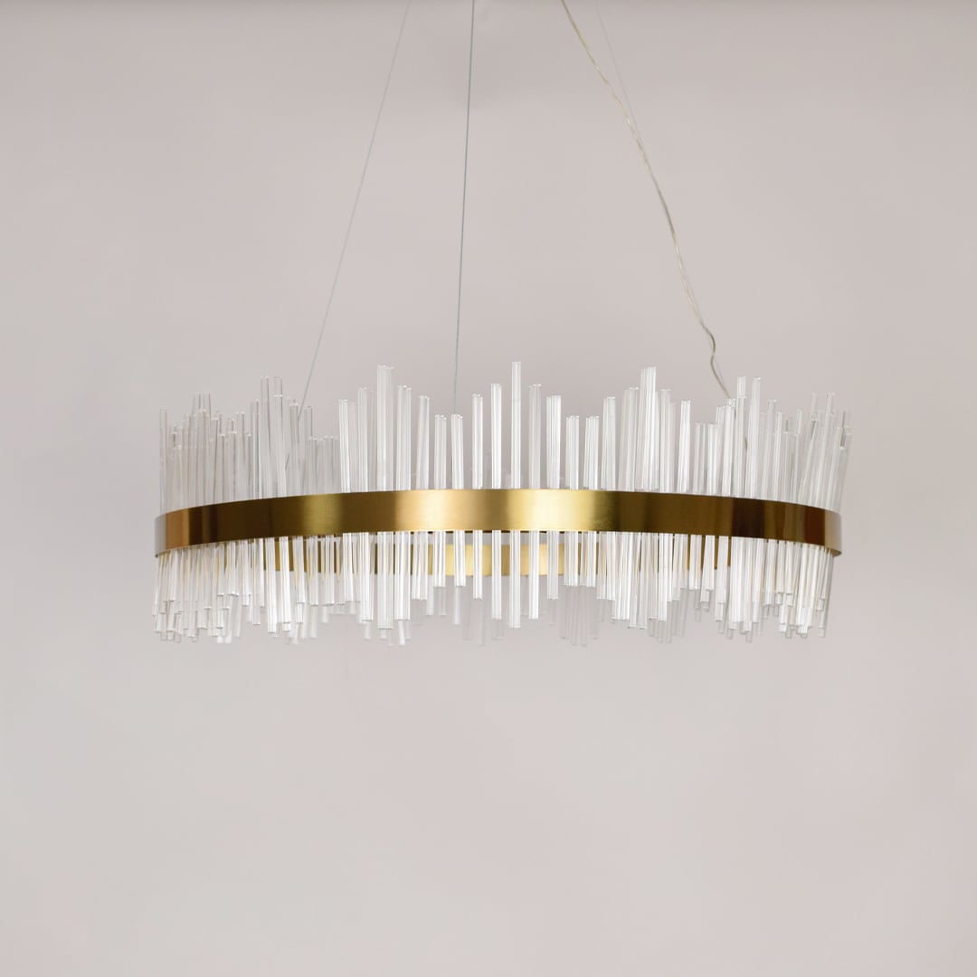 Linear chandelier with clear glass rods and gold metal frame suspended on off white background for luxury interior lighting.