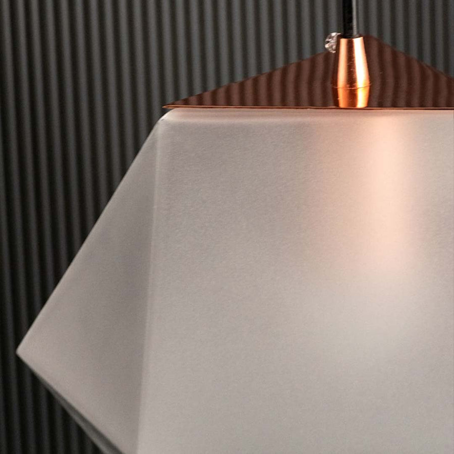Closeup of frosted geometric pendant light showing textured faceted glass surface and warm inner glow for stylish ambient lighting.