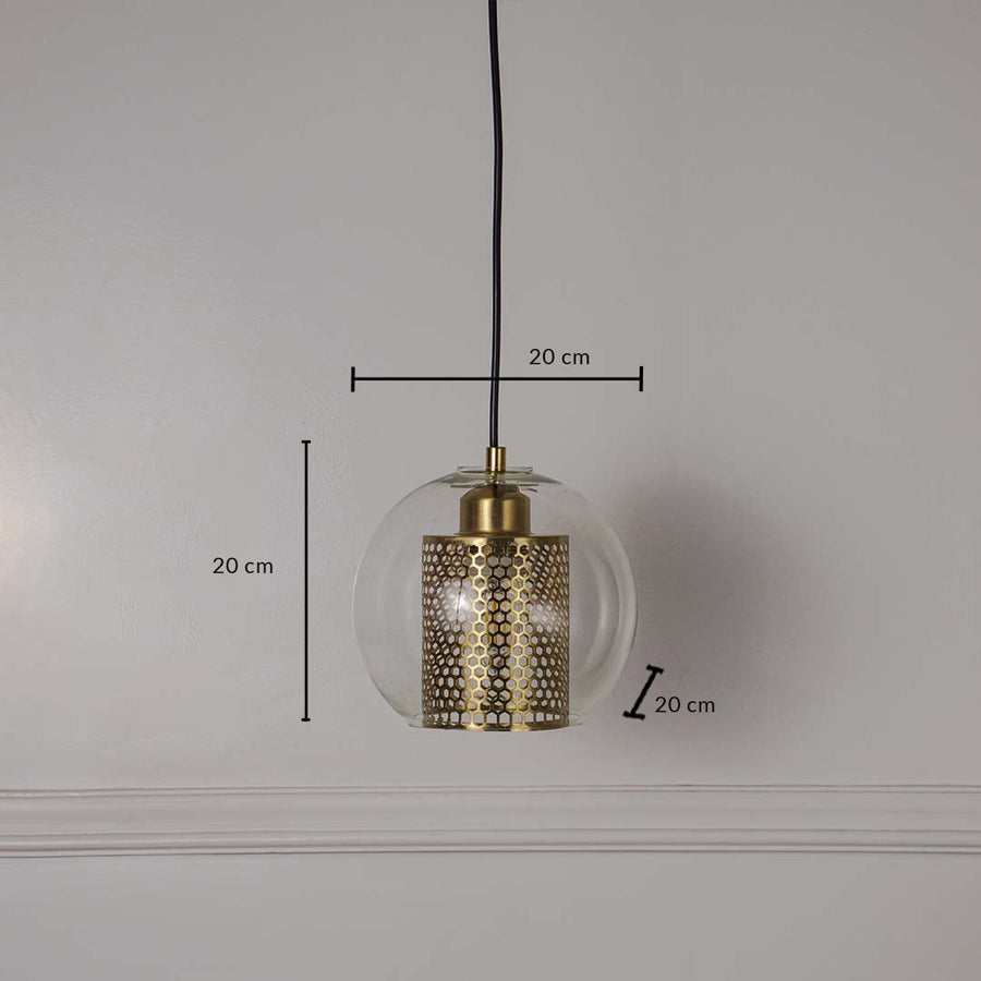 Pendant light with clear glass globe and perforated gold metal inner shade shown with dimensions 20 cm height 20 cm width and 20 cm depth on a white wall.