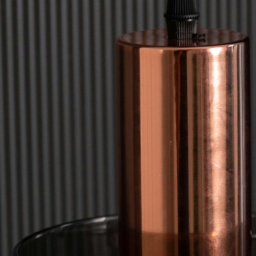 A detailed close view showing the glowing filament bulb inside the smoky glass shade with a polished copper top for a stylish modern look.