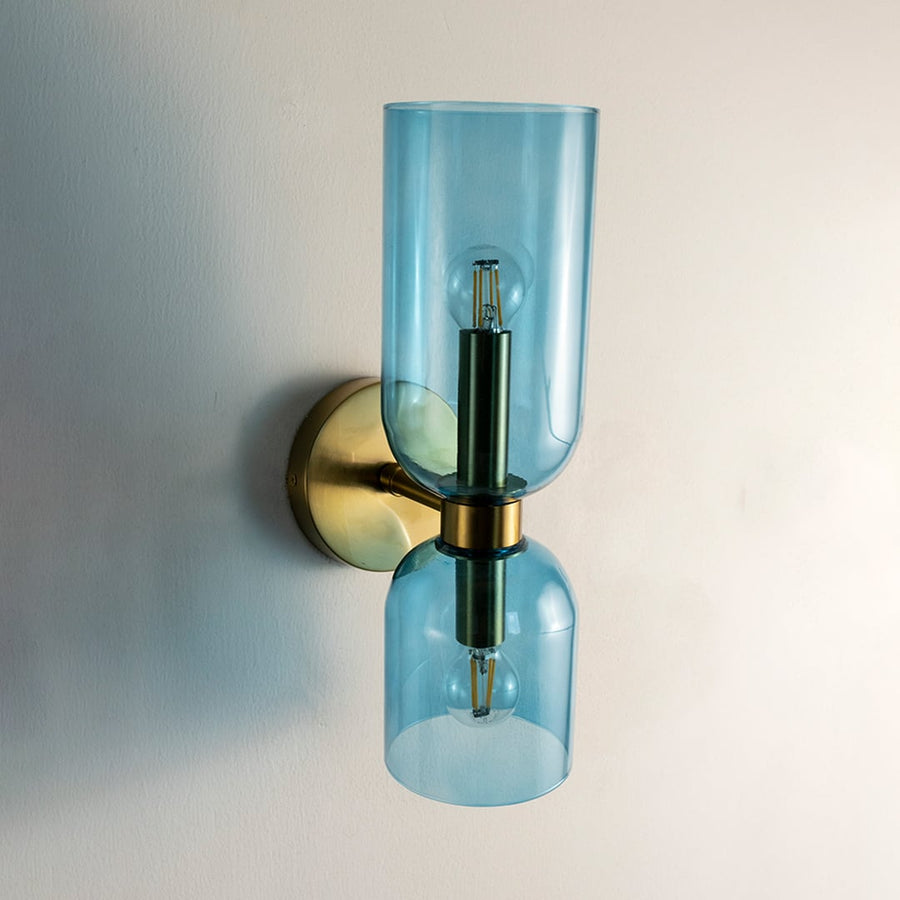 Blue glass wall light with golden base turned off on white wall highlighting elegant modern home decor style.