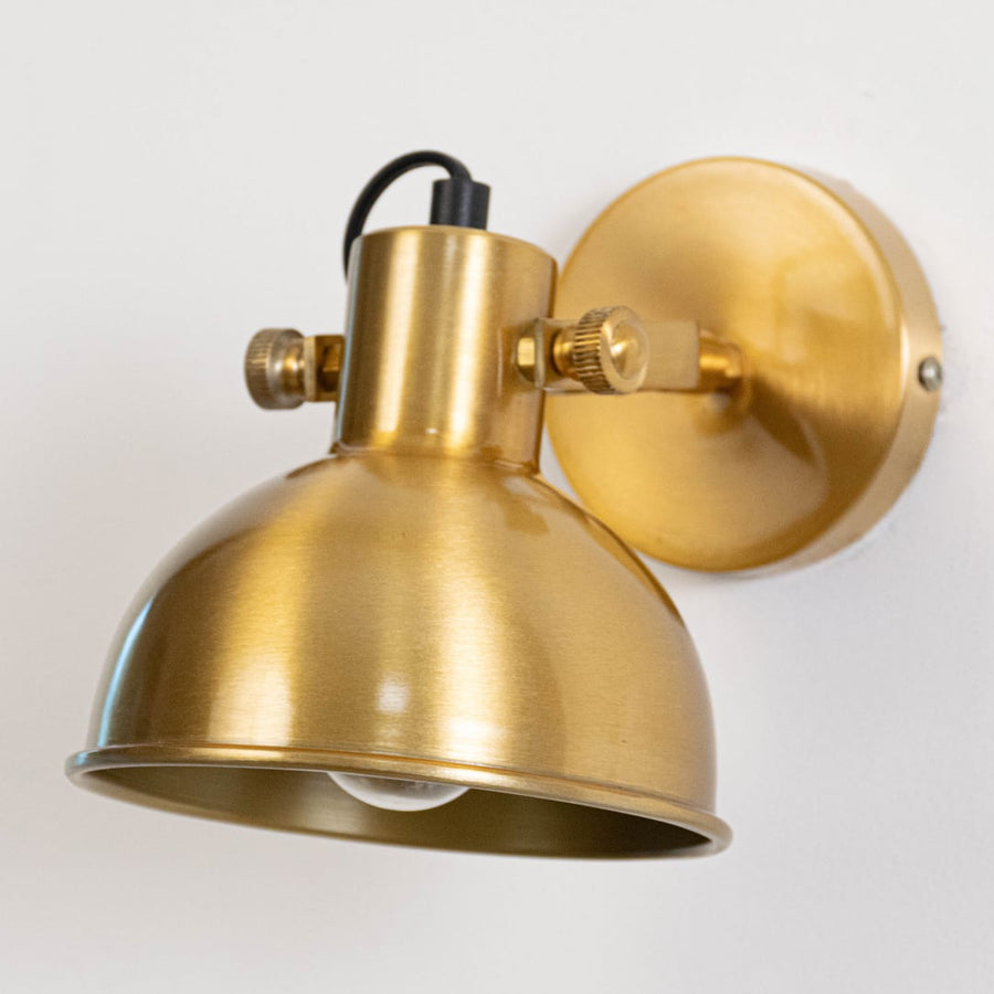 Closeup of adjustable gold metal wall lamp showing angled shade compact form and premium finish for focused wall lighting.