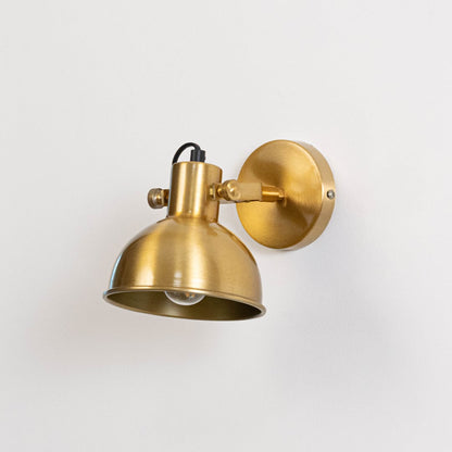 Gold metal wall mounted light switched off on white background emphasizing minimal form and elegant metallic finish.