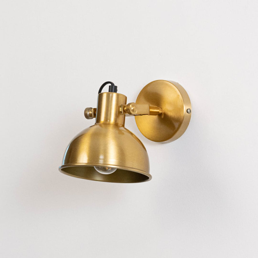 Gold metal wall mounted light switched off on white background emphasizing minimal form and elegant metallic finish.