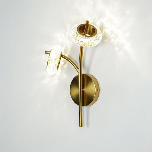 Gold finish wall light with clear textured glass shade emitting bright light perfect for modern wall decor placement on clean background.