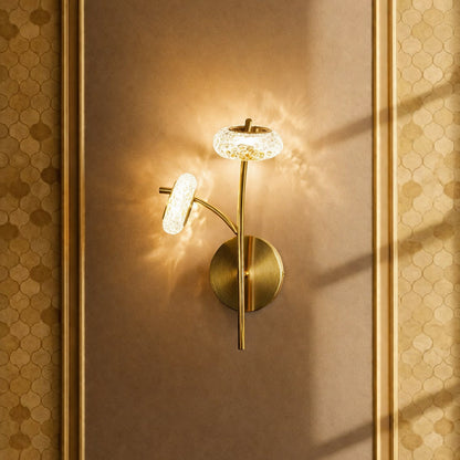 Gold metal wall light with crystal glass shade casting warm glow ideal for bedroom or hallway wall decor in elegant interior setting.