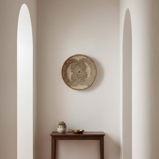 Decorative woven wall basket displayed above a minimal console table framed by arched light adding calm balance and artisanal appeal.