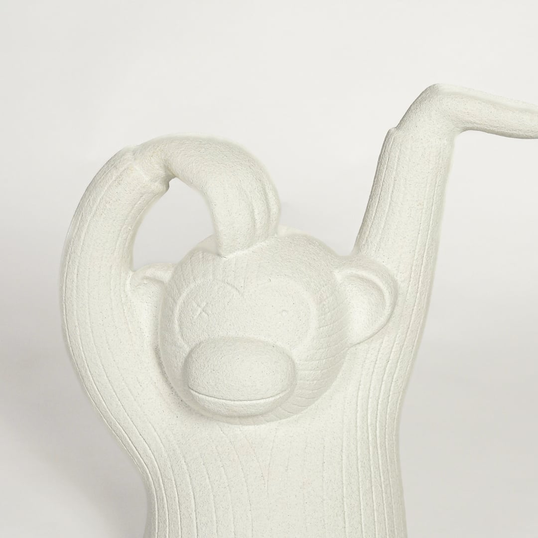 Close up of white monkey sculpture showing carved texture facial detail and raised arm design modern artistic decor piece.