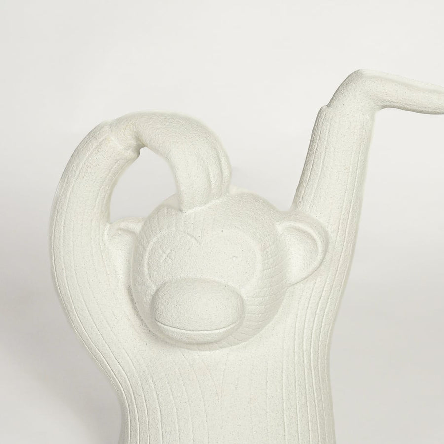 Close up of white monkey sculpture showing carved texture facial detail and raised arm design modern artistic decor piece.