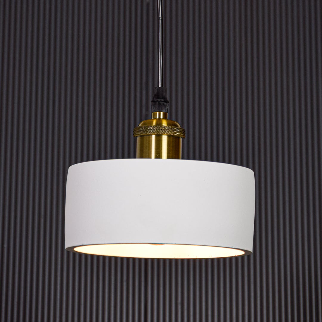 White metal pendant light with gold holder switched on against black background creating focused modern ambient lighting.