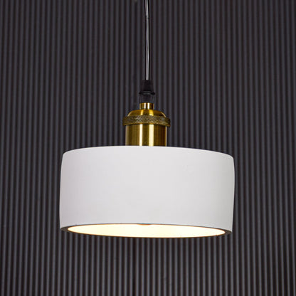 White metal pendant light with gold holder switched on against black background creating focused modern ambient lighting.