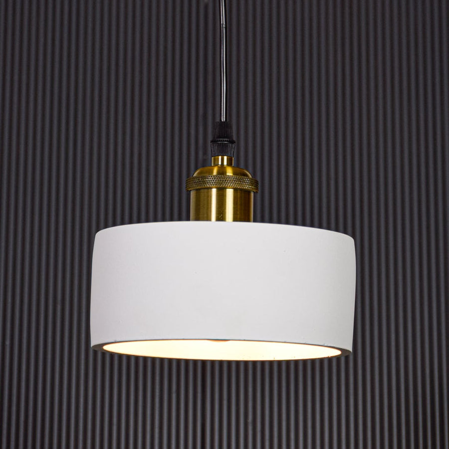 White metal pendant light with gold holder switched on against black background creating focused modern ambient lighting.