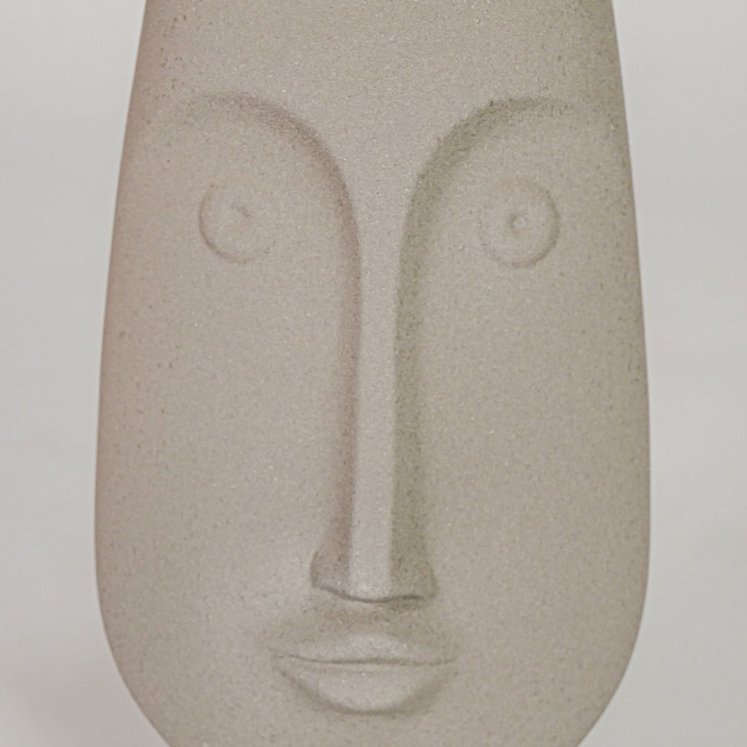 Closeup image of beige ceramic abstract face sculpture for modern shelf decor styling with matte finish display.