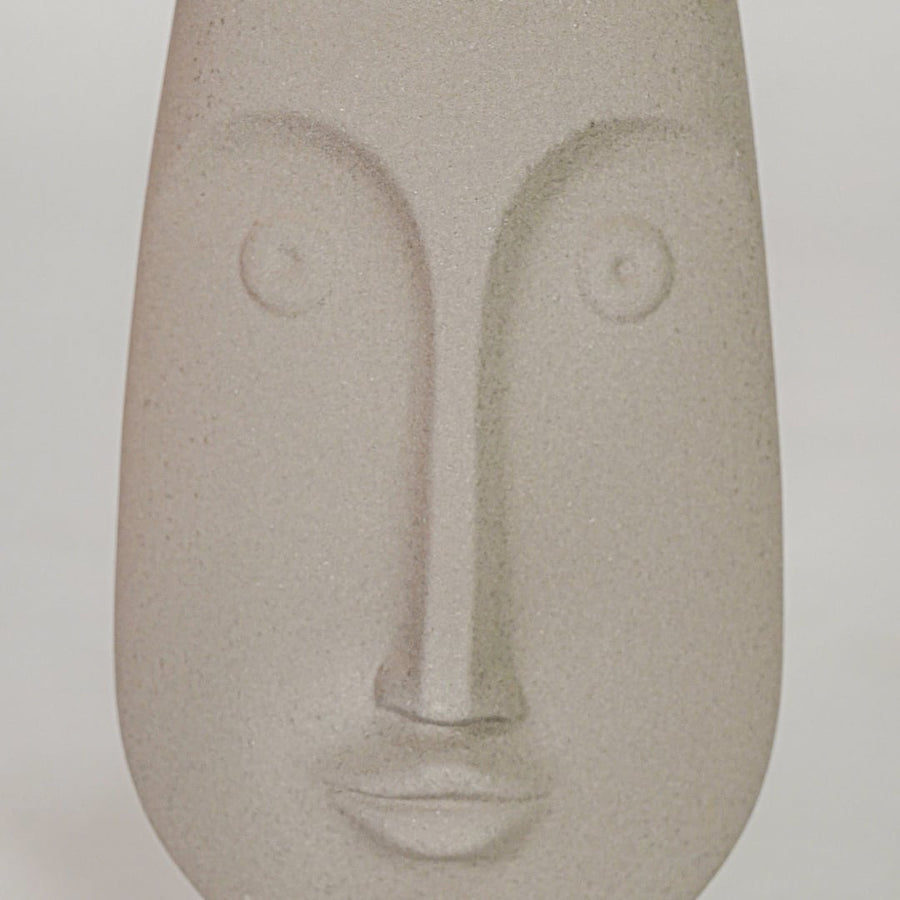 Closeup image of beige ceramic abstract face sculpture for modern shelf decor styling with matte finish display.