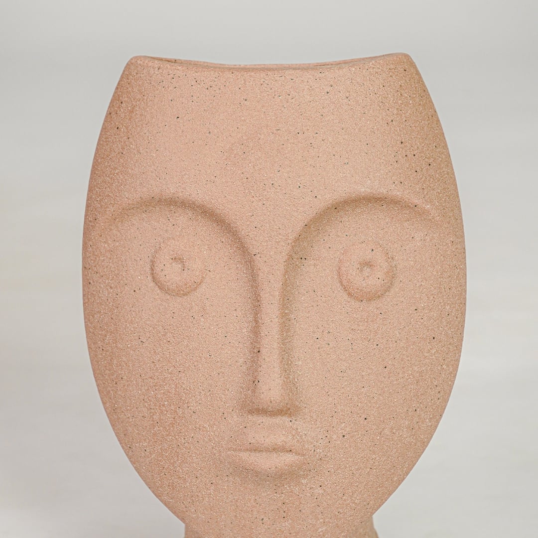Closeup image of peach ceramic face decor sculpture for modern tabletop styling with artistic matte texture finish.