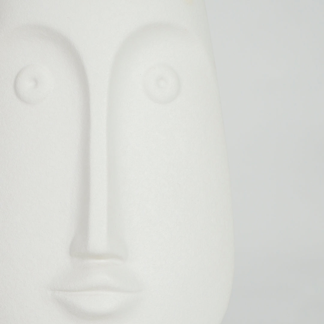 Closeup image of white ceramic abstract face sculpture for modern shelf decor styling with smooth matte finish.