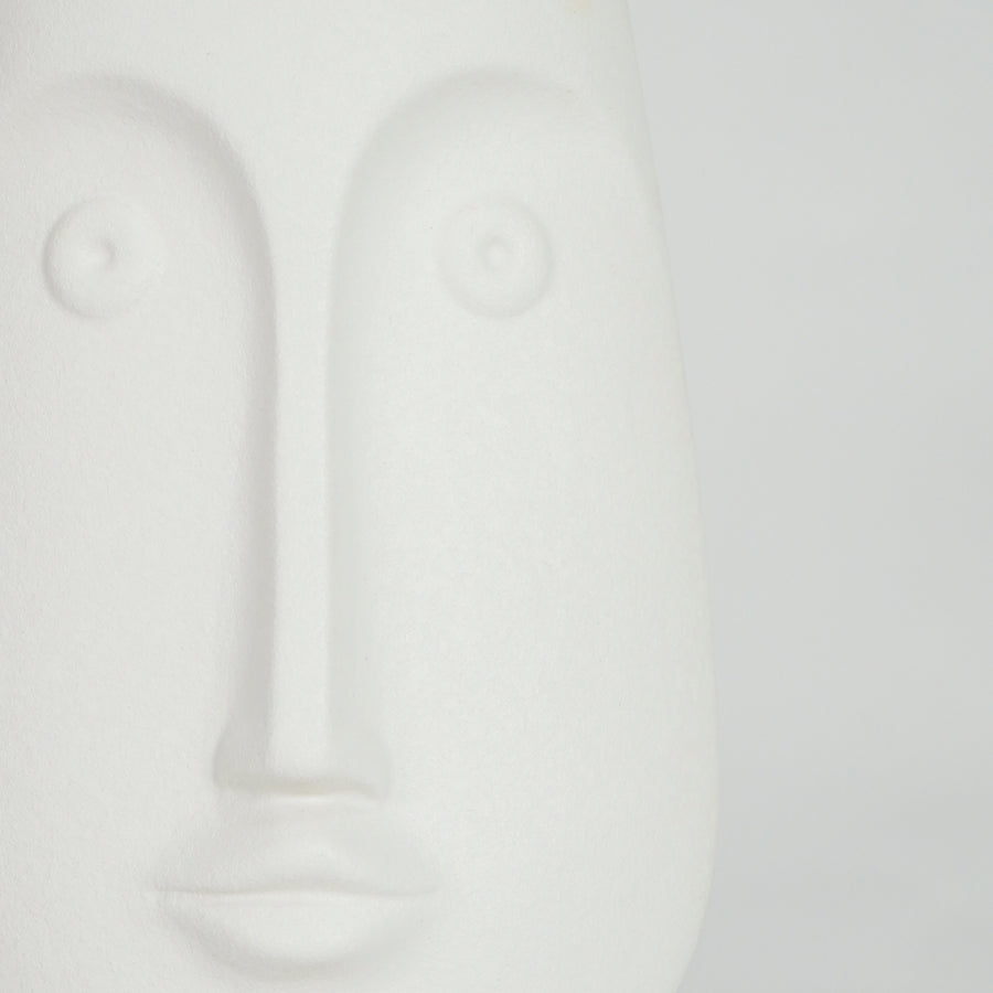 Closeup image of white ceramic abstract face sculpture for modern shelf decor styling with smooth matte finish.