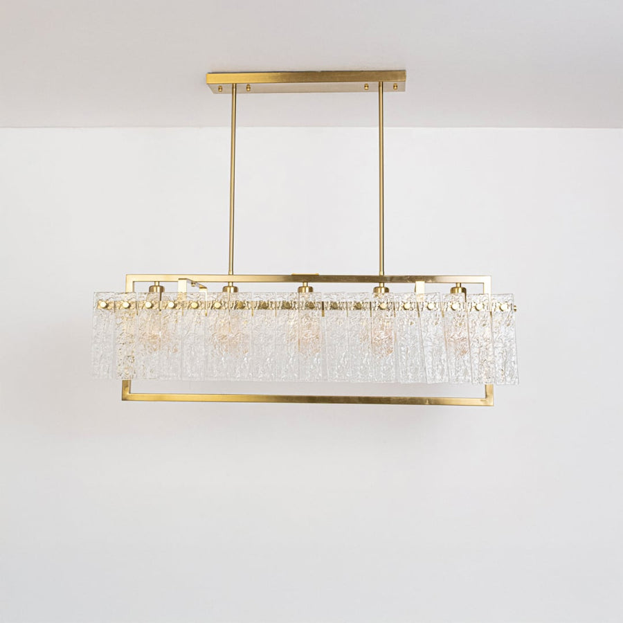 Gold rectangular chandelier with crystal accents turned off on white background displaying elegant dining room fixture design.