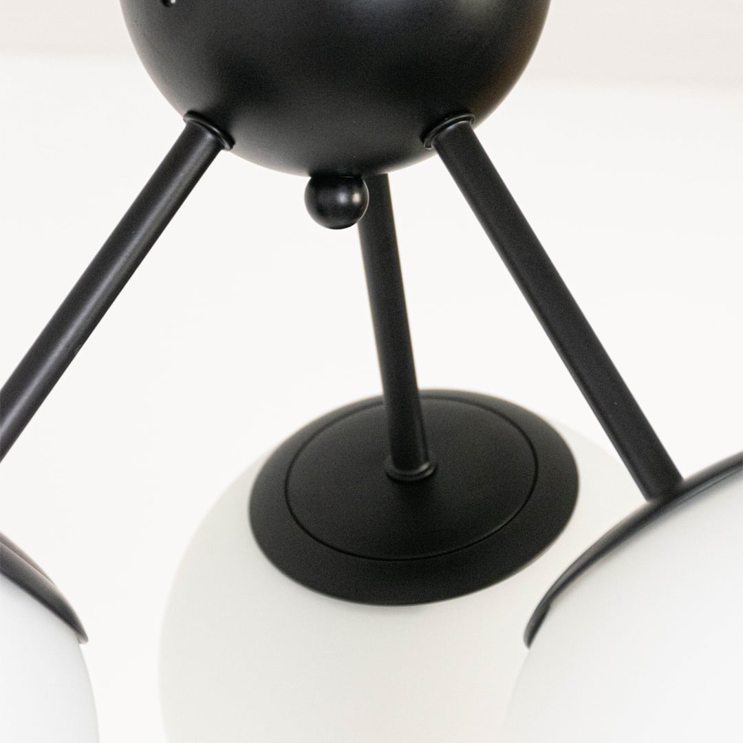 Closeup of ceiling light with three frosted glass globes on black frame for elegant modern ceiling lighting home decor.