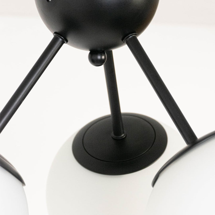 Closeup of ceiling light with three frosted glass globes on black frame for elegant modern ceiling lighting home decor.