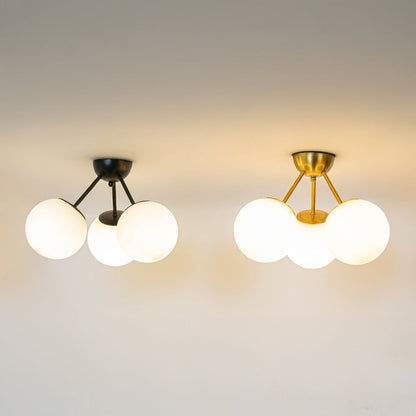 Black and gold ceiling lights with triple frosted glass globes glowing brightly on white background for modern home decor.