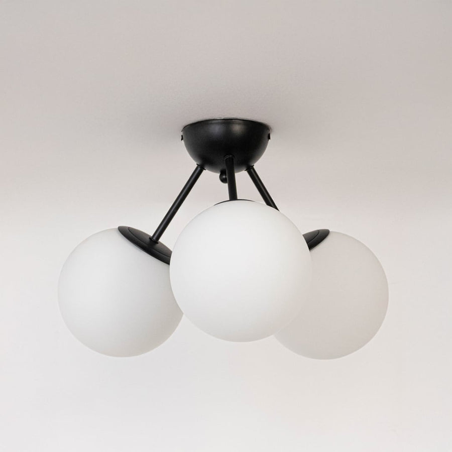 Black ceiling light with three frosted glass globes in off mode displayed on white background for modern ceiling lighting.