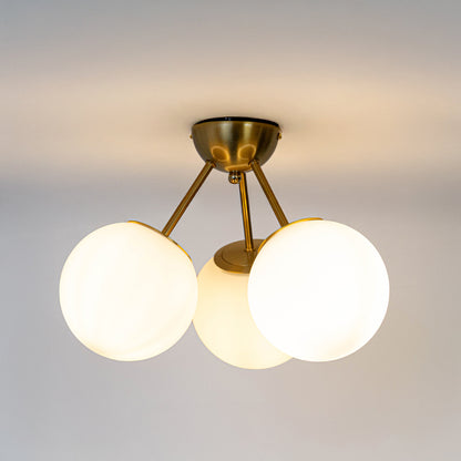 Modern gold metal ceiling light with three white glass globes for elegant bedroom and premium interior decor spaces.