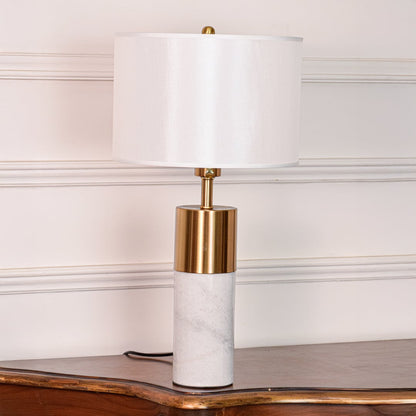 White marble table lamp shown unlit on white background featuring brass metal accent and clean cylindrical modern design.