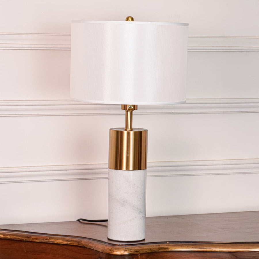White marble table lamp shown unlit on white background featuring brass metal accent and clean cylindrical modern design.