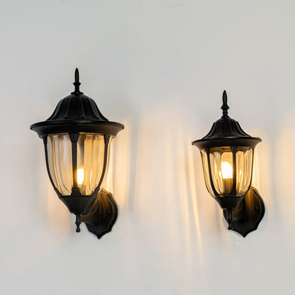 Black metal and clear glass outdoor wall lantern lights grouped on wall creating warm porch glow shown Light on white BG.v
