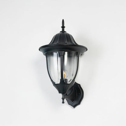Black outdoor wall lantern switched off on white background showing traditional coach style exterior light fixture hardware.