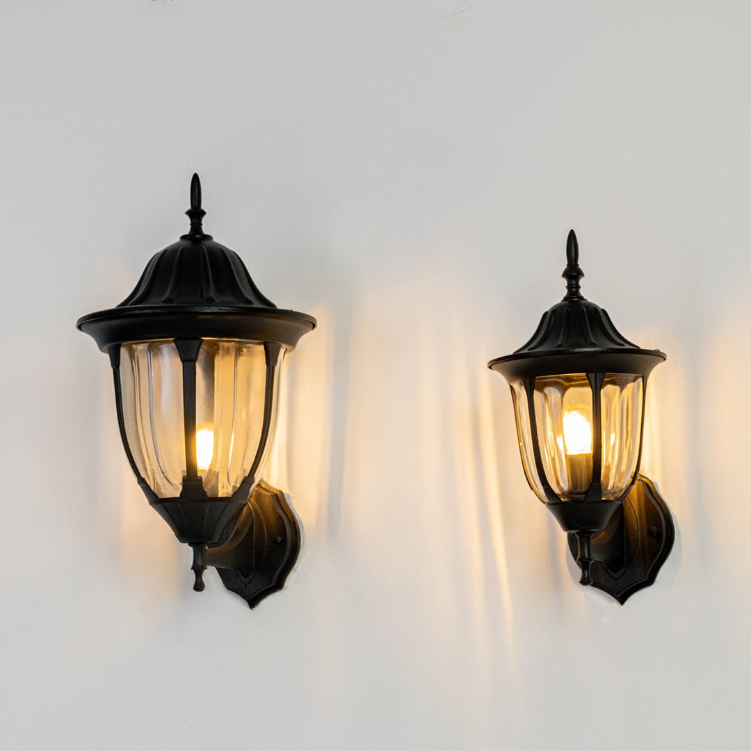 Black metal outdoor wall lights on white background with warm glow for elegant exterior entryway decor.