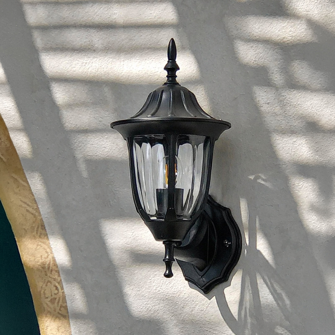 Black metal outdoor wall light lifestyle image with ribbed glass shade for elegant exterior entryway decor.