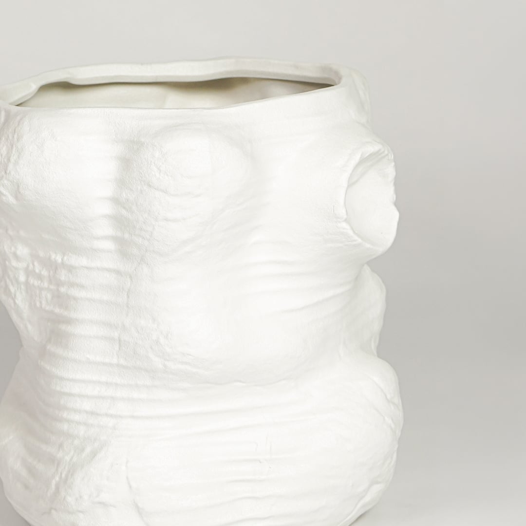 Closeup of matte white ceramic face vase with sculpted abstract features ideal for modern living room shelf or console decor styling.