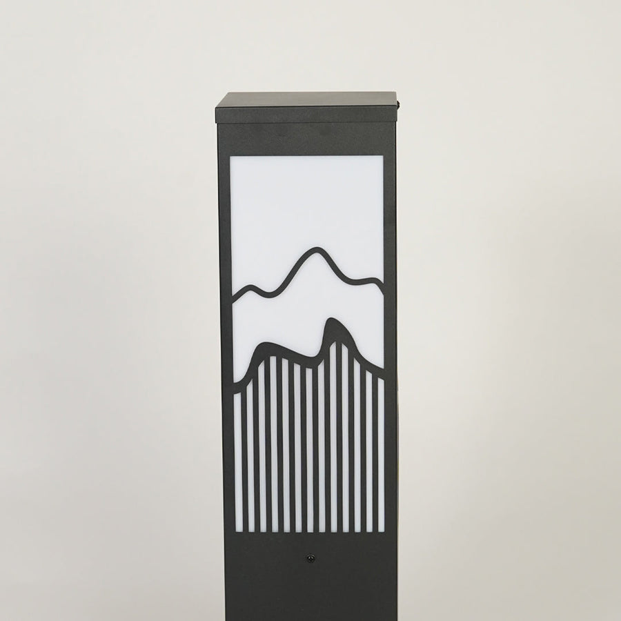 Modern outdoor garden light with rectangular metal frame and patterned glass panel creating soft ambient lighting for pathways.