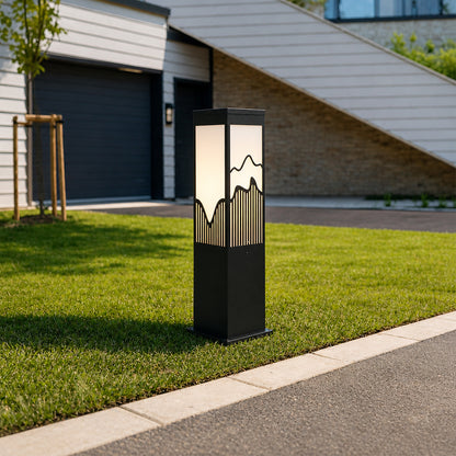 Outdoor bollard light with black metal body installed along pathway in garden setting creating soft ambient exterior lighting.