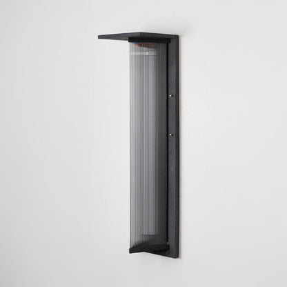 Tall modern wall light with matte black frame and ribbed glass front shown off on plain white background.
