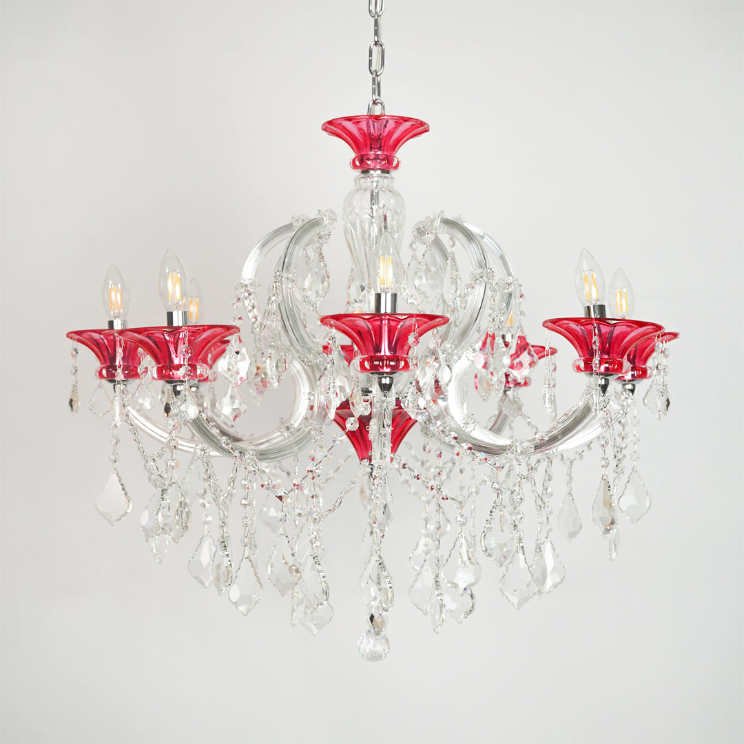 White background image of red and clear glass baccarat style chandelier for elegant dining room decor styling with unlit arms.