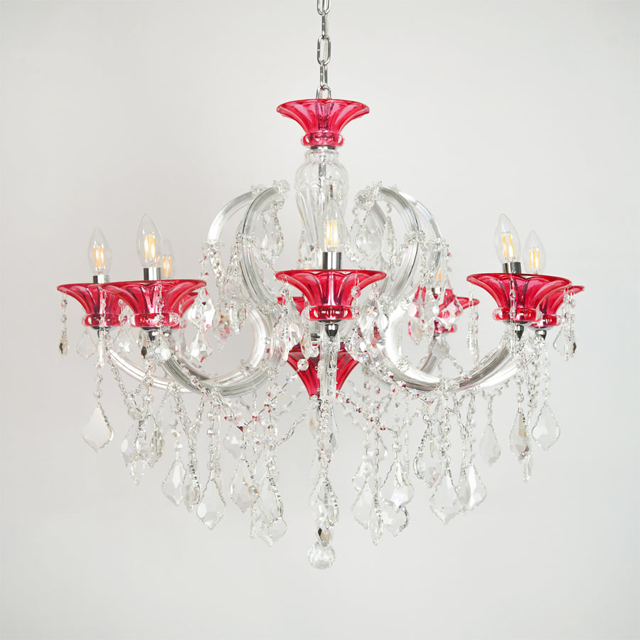 White background image of red and clear glass baccarat style chandelier for elegant dining room decor styling with unlit arms.