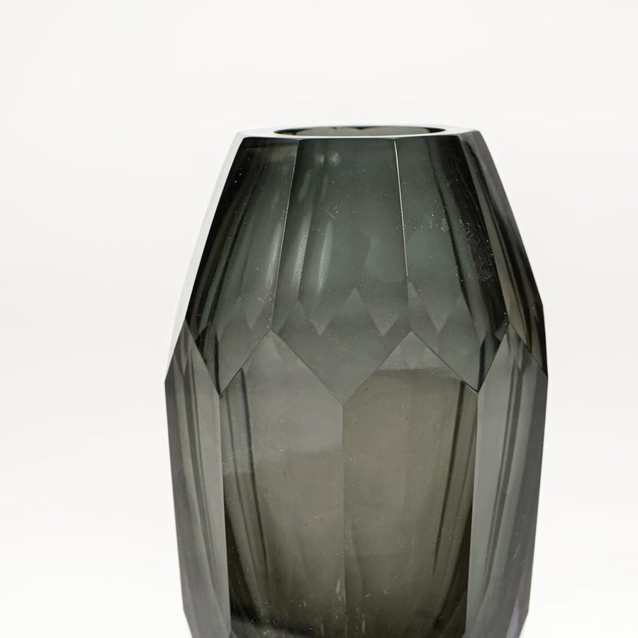 Close view of grey tinted glass decorative vase highlighting faceted geometric texture and smooth glossy finish.