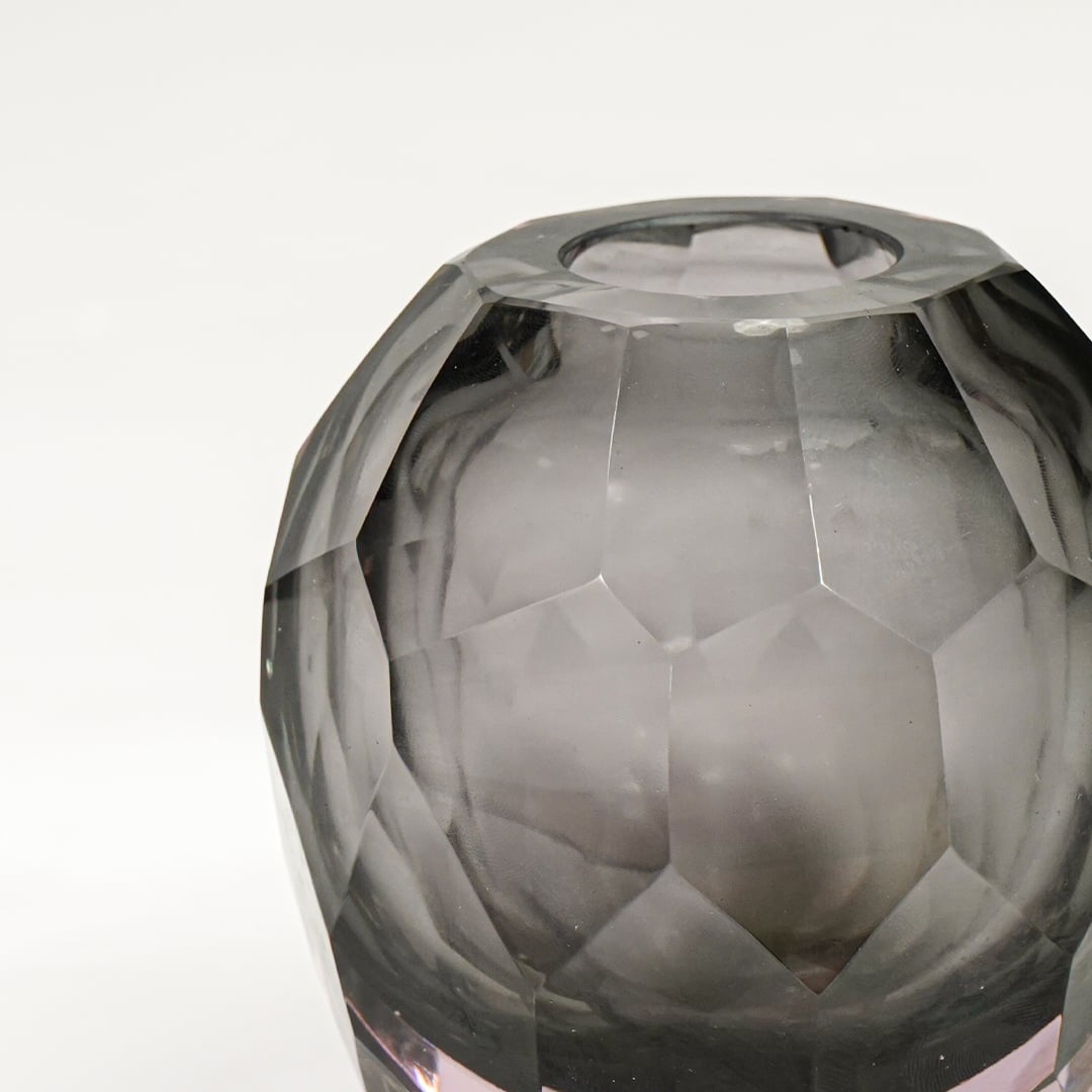 Close view of grey glass decorative bowl highlighting faceted geometric texture and refined glossy finish.
