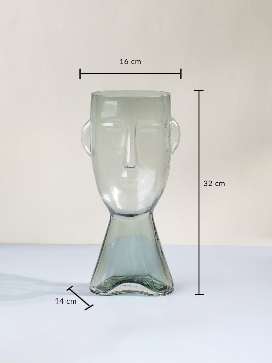 Face shaped glass vase 32 cm height 16 cm width 14 cm depth transparent finish modern abstract design light on white background.