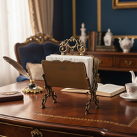 Antique metal napkin holder styled on classic wooden writing desk with vintage decor books teacup and elegant study setting creating refined old world charm.