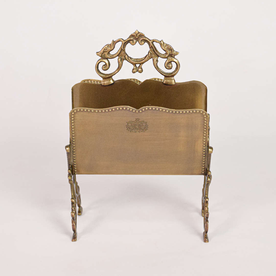 Antique metal napkin holder shown on deep white background emphasizing sculpted frame curved feet and traditional design with dramatic studio contrast.