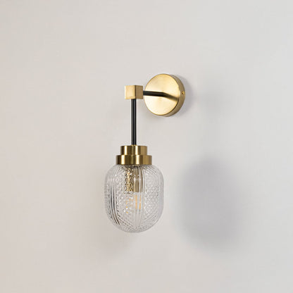 Minimalist gold and black wall sconce with textured glass shade switched off displayed on plain white background for product image.