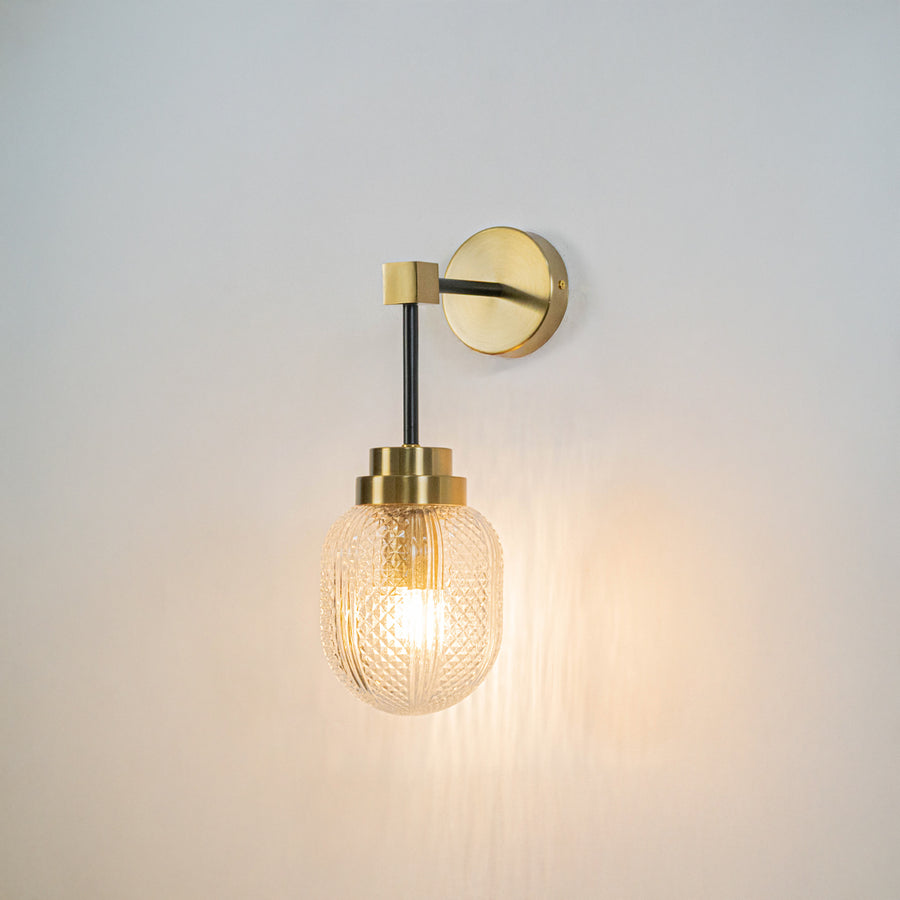 Minimal wall light with gold mount and exposed filament bulb on neutral wall background modern lighting perfect for bedroom living room decor.

