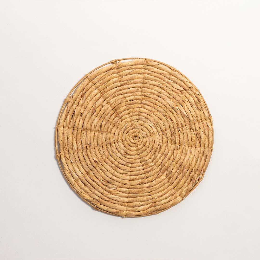 Round handcrafted solid natural wicker seagrass wall basket with woven spiral design on white background product image.