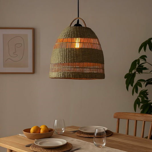 Woven rattan pendant light glowing warmly above a wooden dining table with tableware plants and wall art creating a cozy natural modern dining room ambiance.