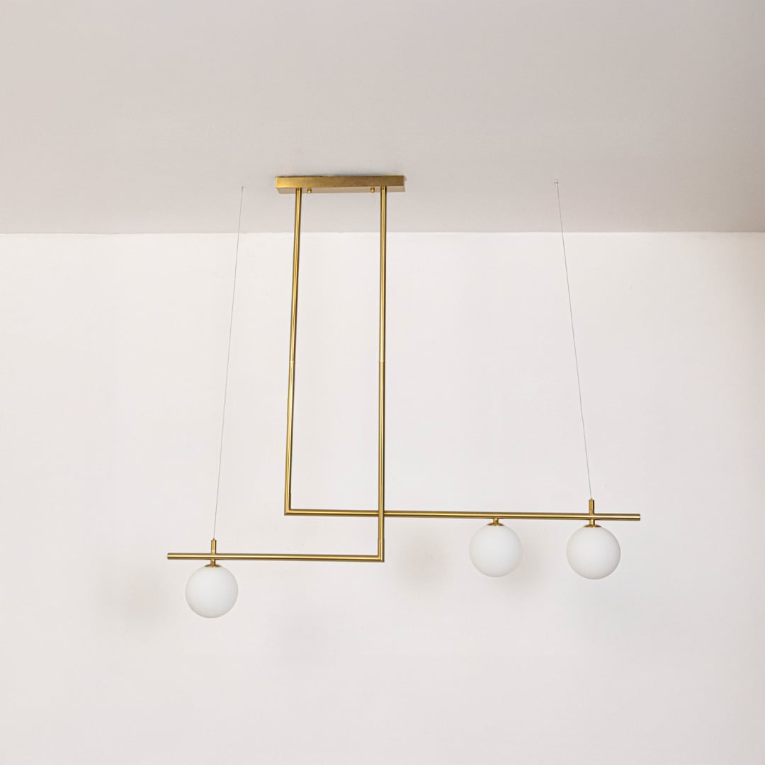 Gold pendant light with frosted glass globes and linear frame in off mode displayed on white background for decor view.